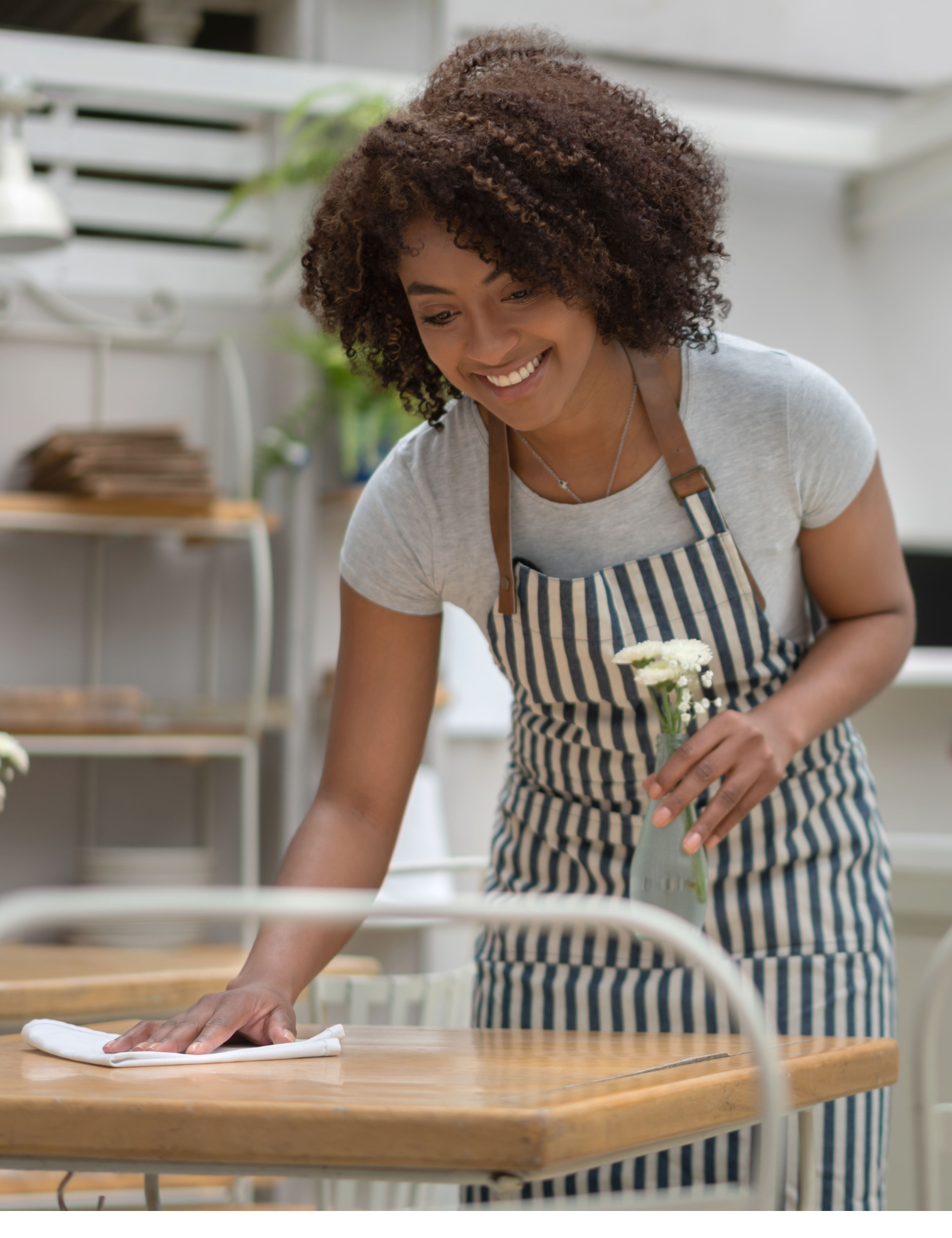 Happy waitress cleaning the tables at a restaurant