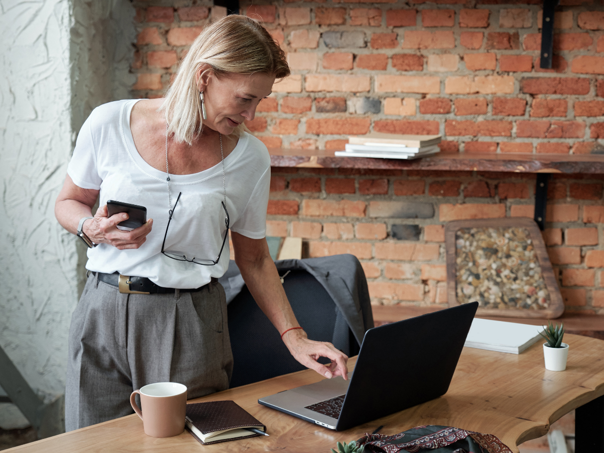 lady standing at desk and saving document through her laptop