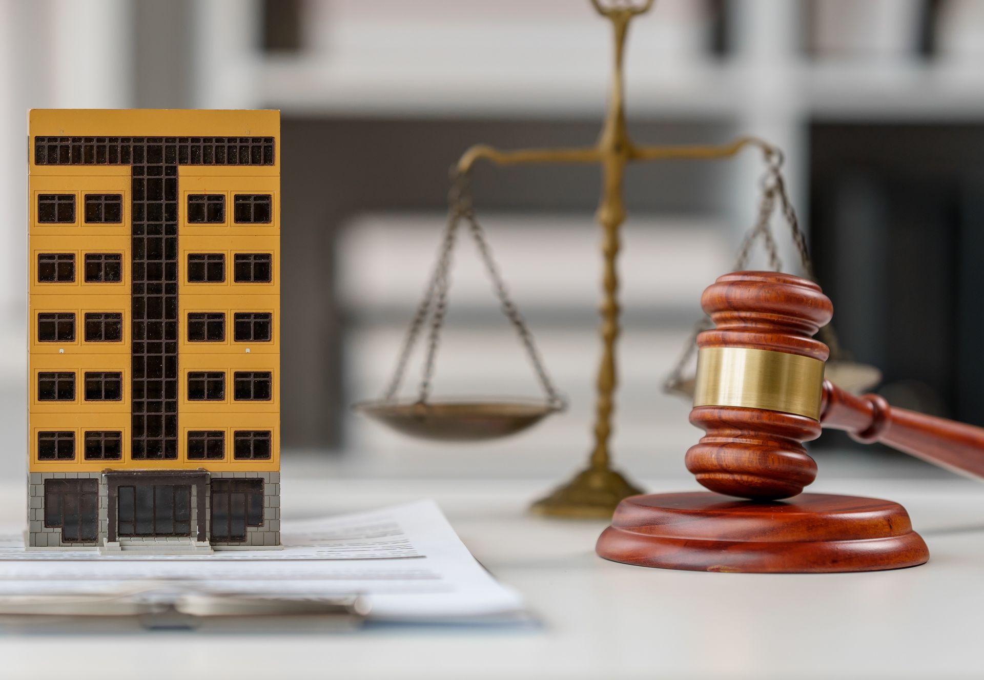 Court gavel and scales beside a model apartment building on legal documents