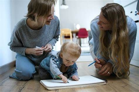 Two women are kneeling on the floor with a baby.