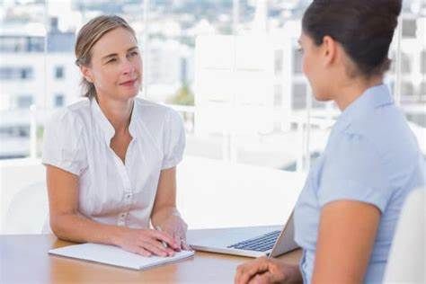 Two women are sitting at a table having a conversation.