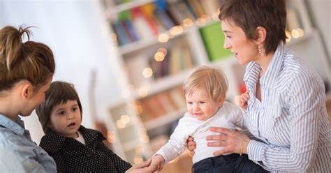 A woman is holding a baby in her arms while talking to two other women.