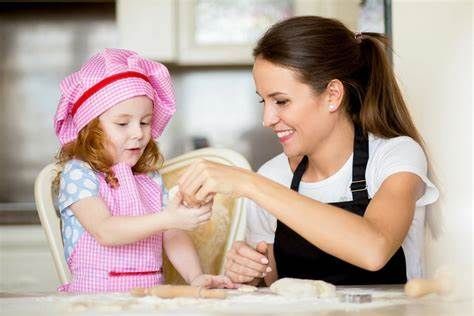 A woman and a little girl are preparing food in a kitchen.