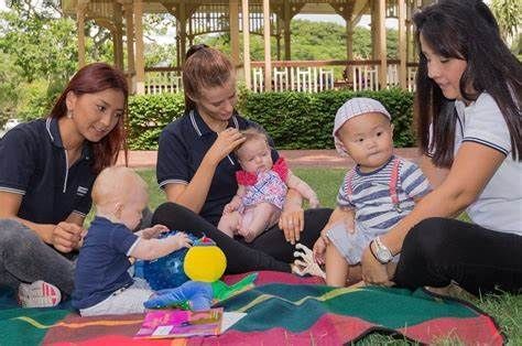 A group of women are sitting on a blanket with their babies.