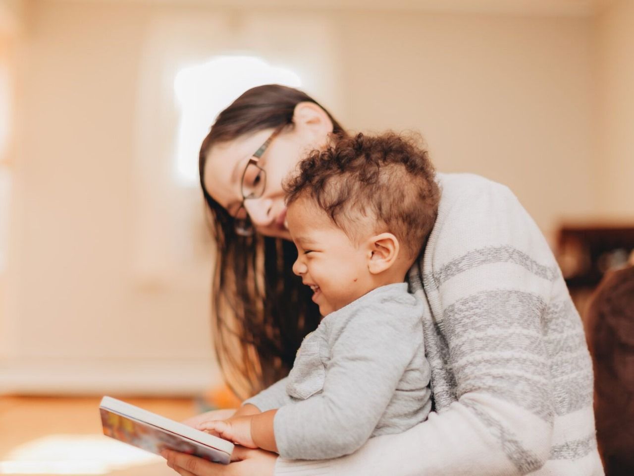 A woman is holding a baby and reading a book to him.