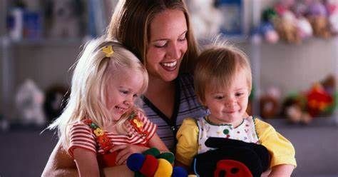 A woman is holding two children and a stuffed animal.
