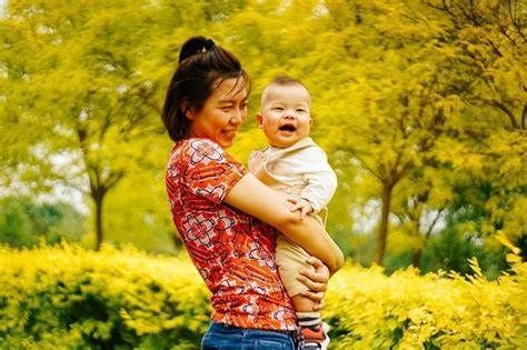 A woman is holding a baby in her arms in a park.