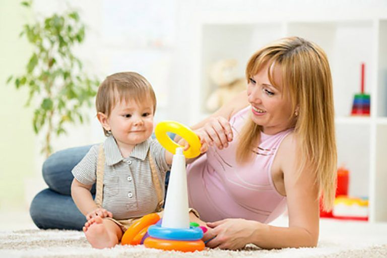 A woman and a baby are playing with toys on the floor.