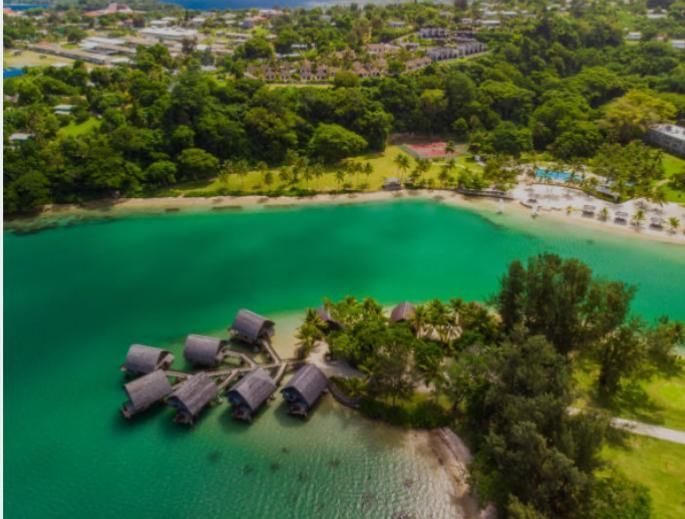 An aerial view of a tropical island surrounded by water and trees.