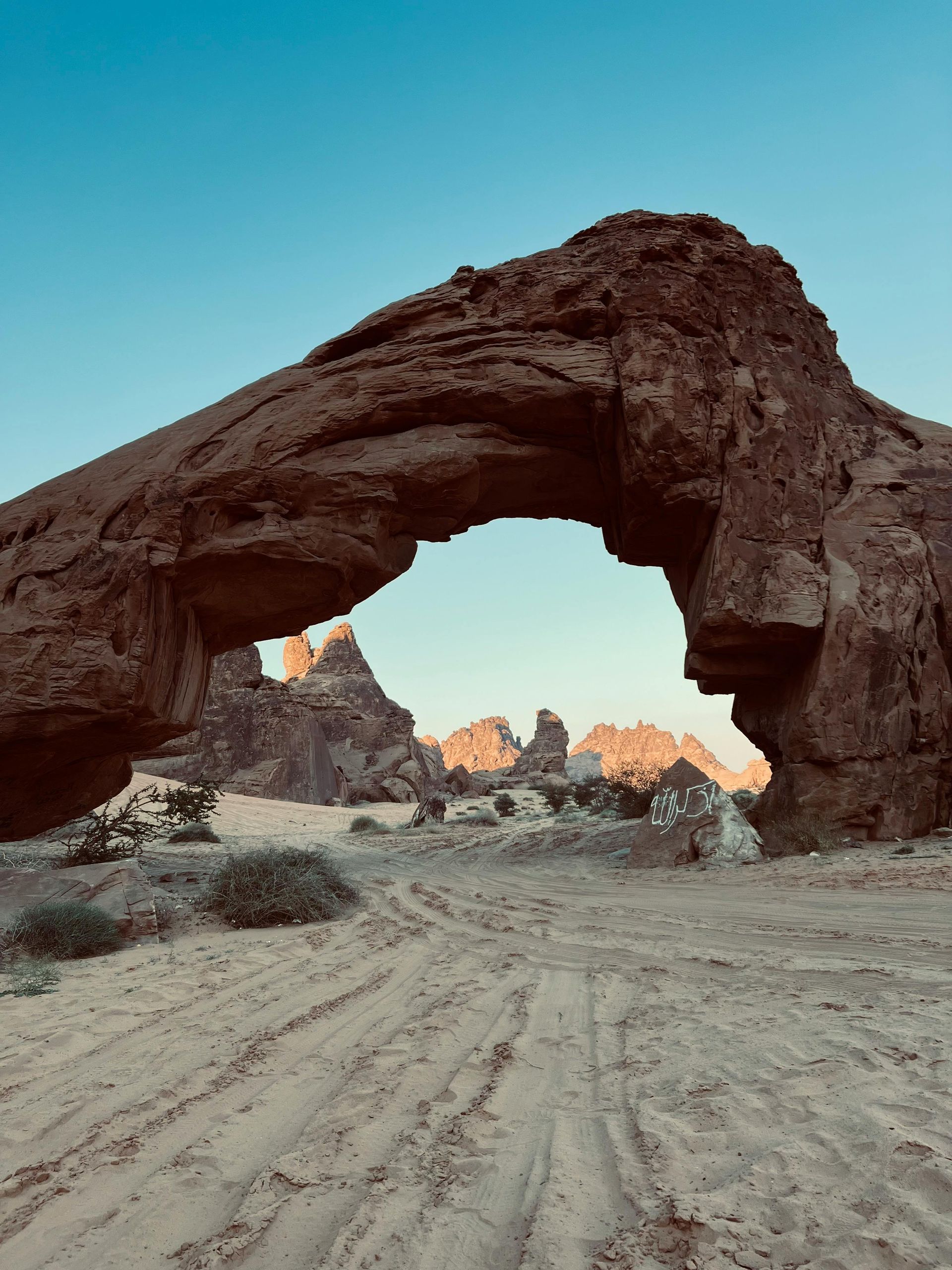 A large rock arch in the middle of a desert.