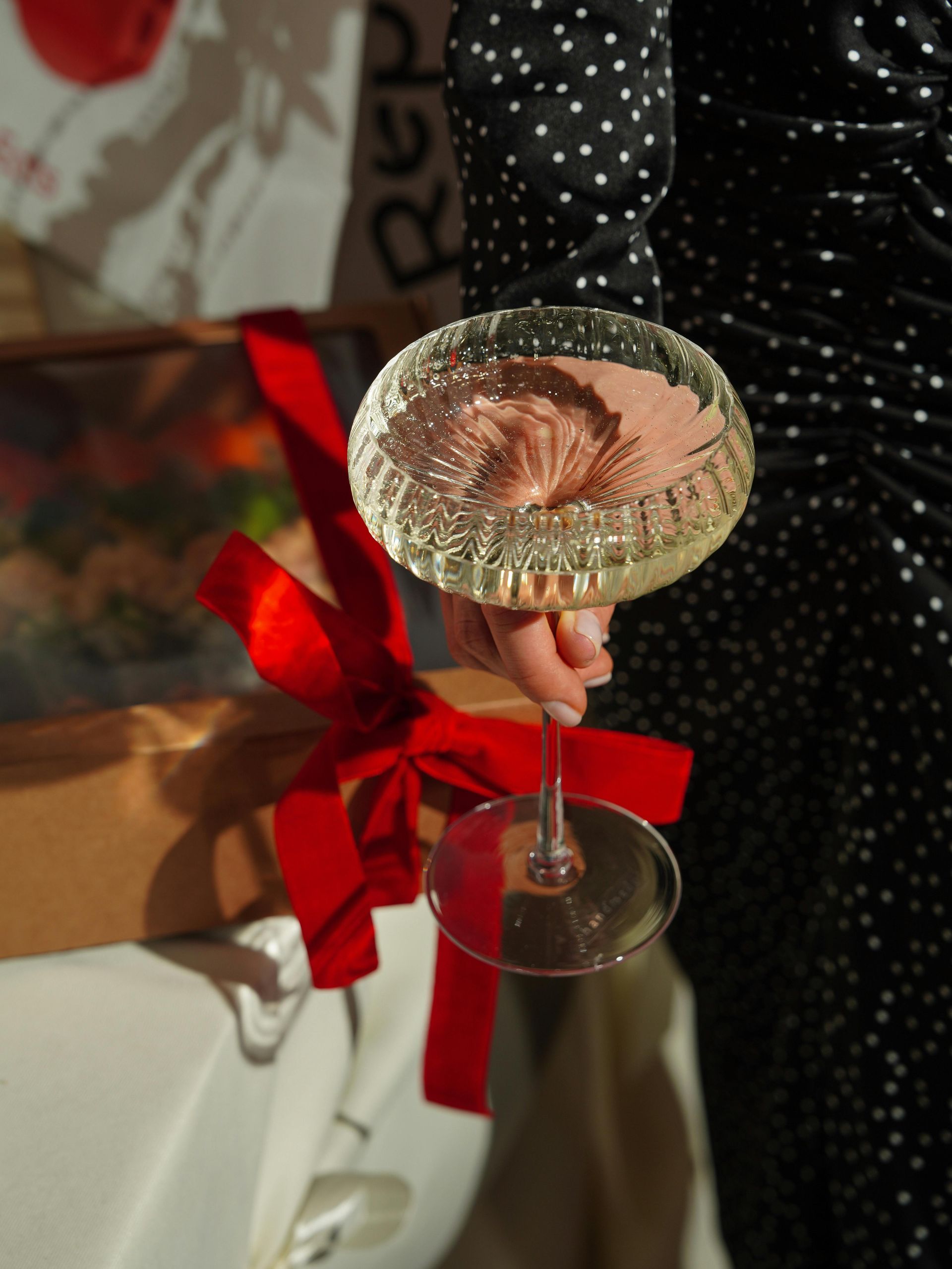 A woman is holding a glass of champagne with a red bow.