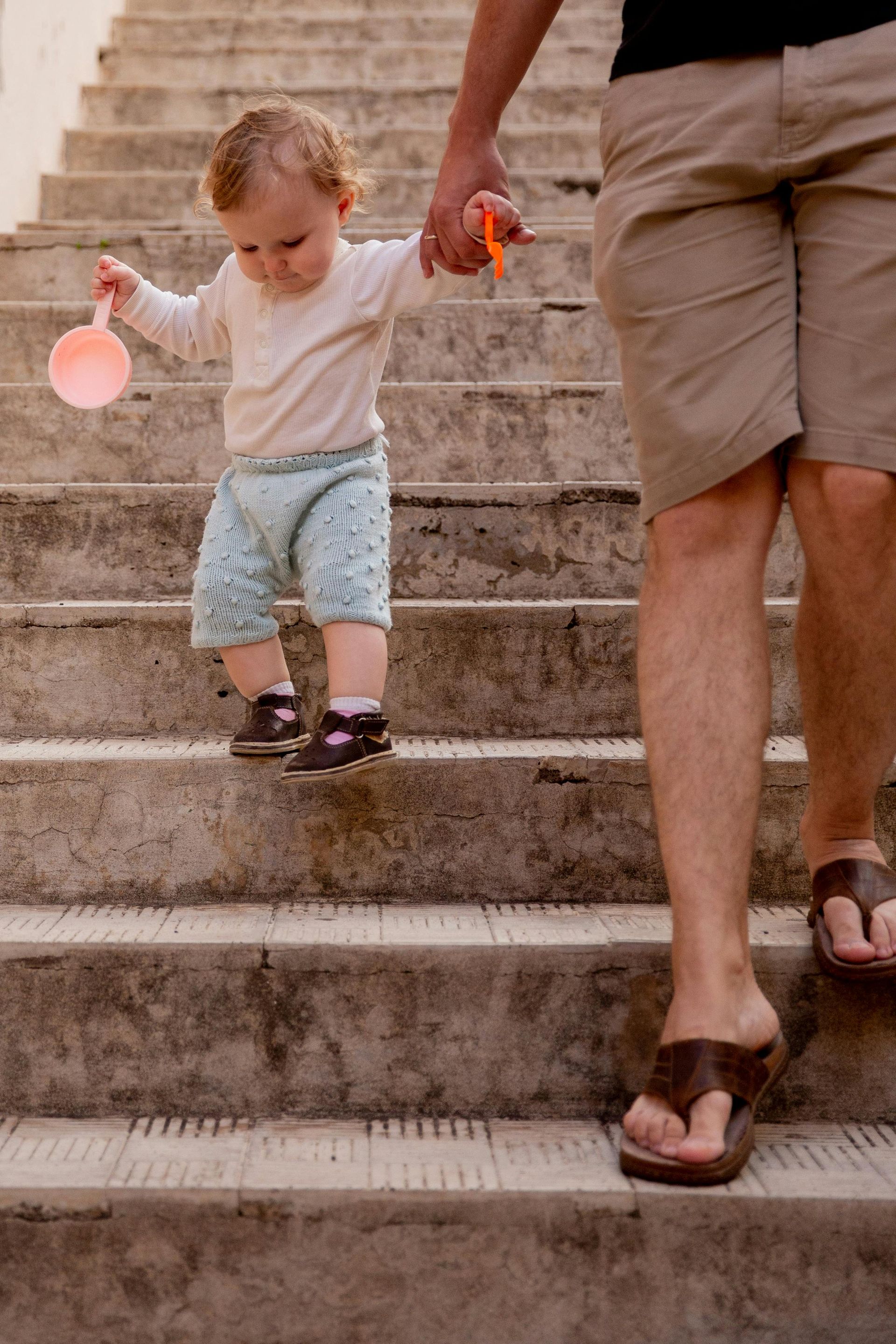 A man is holding a baby 's hand while walking up a set of stairs.