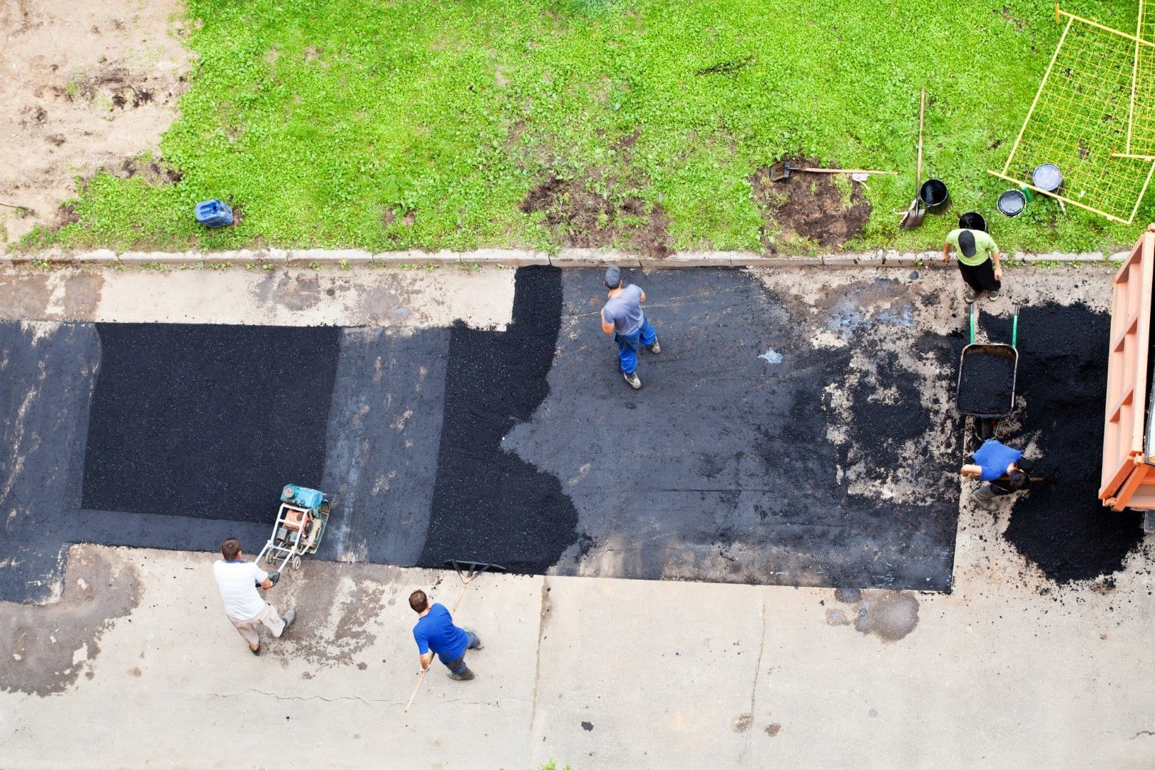 An aerial view of a group of people laying asphalt on a sidewalk.