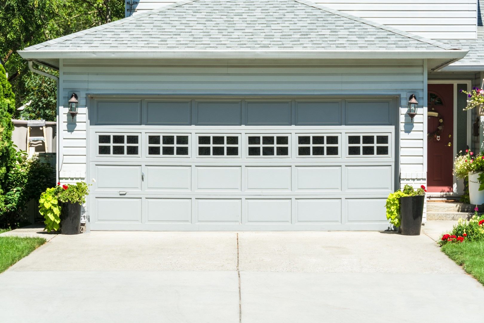 A white garage door is sitting in front of a house.