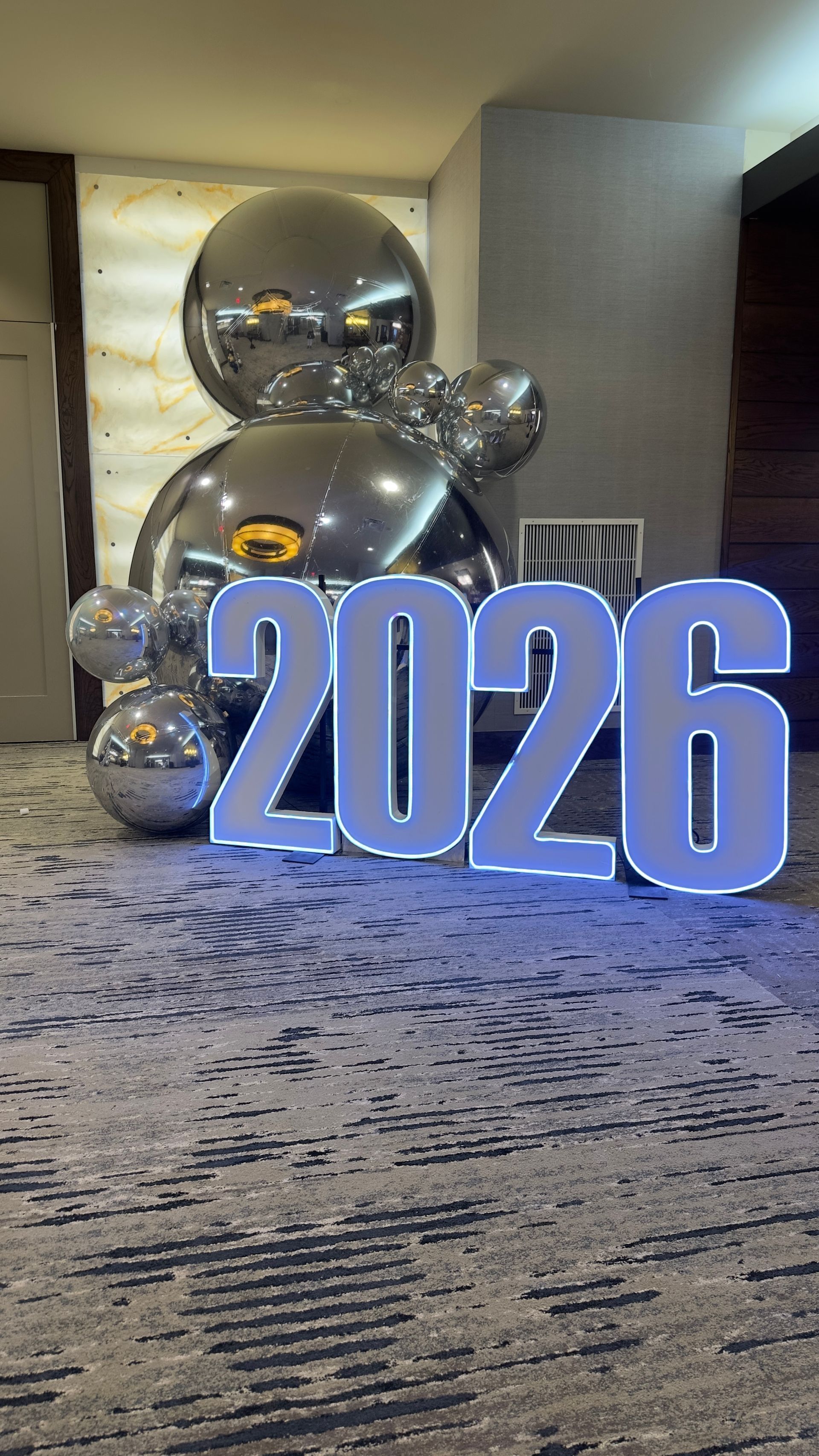 Blue “2026” sign with silver balloon decorations in a hotel lobby