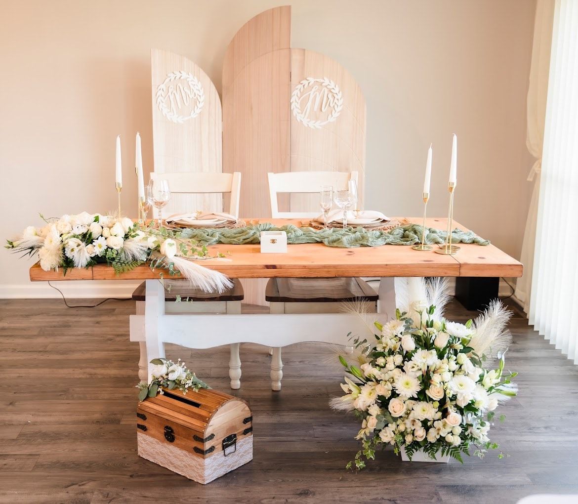 Rustic wedding table with white chairs, floral arrangements, and candles in a softly lit room