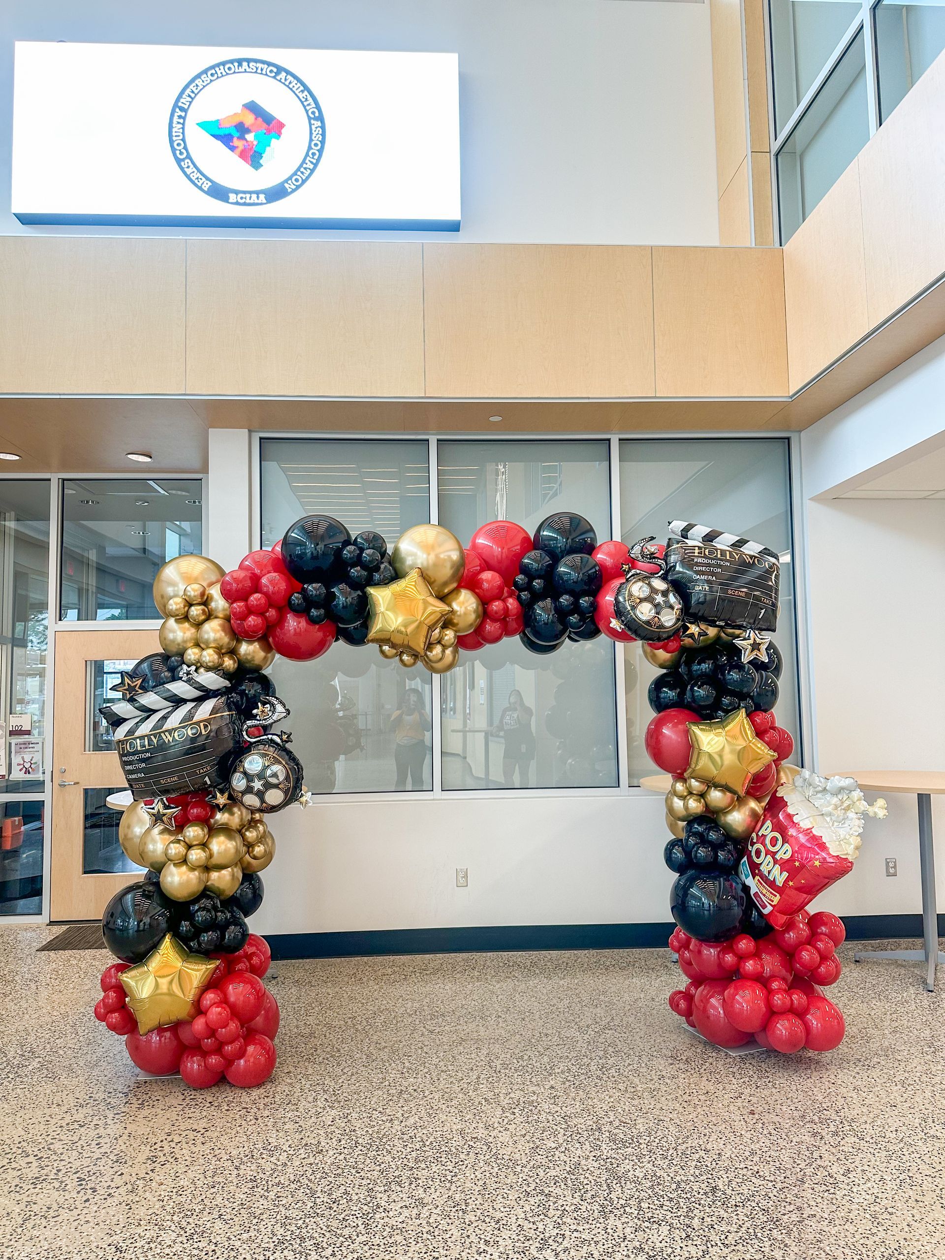 Balloon arch in black, gold, and red, framing an entryway.