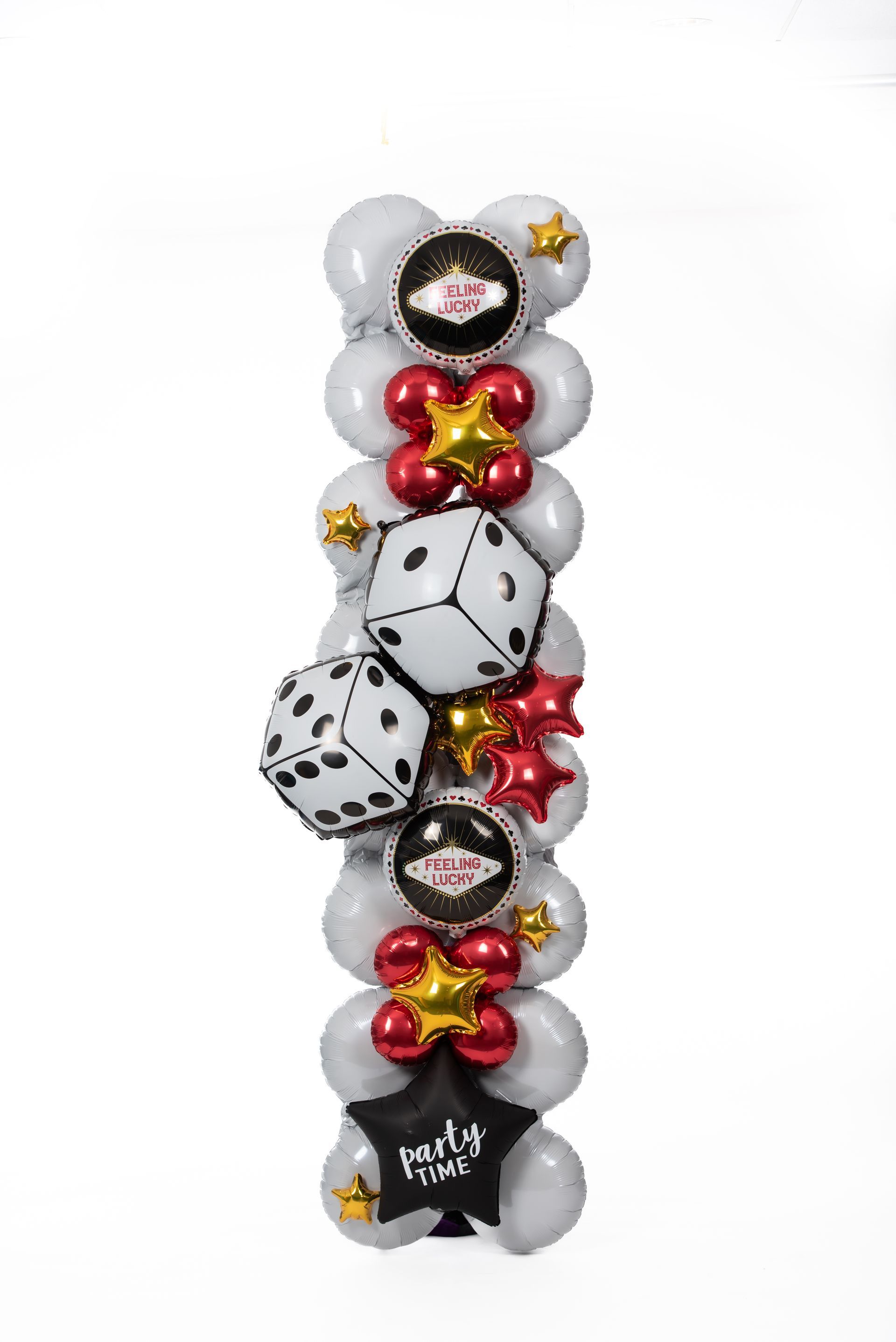Vertical balloon sculpture with white, black, silver, red, and yellow balloons and dice accents