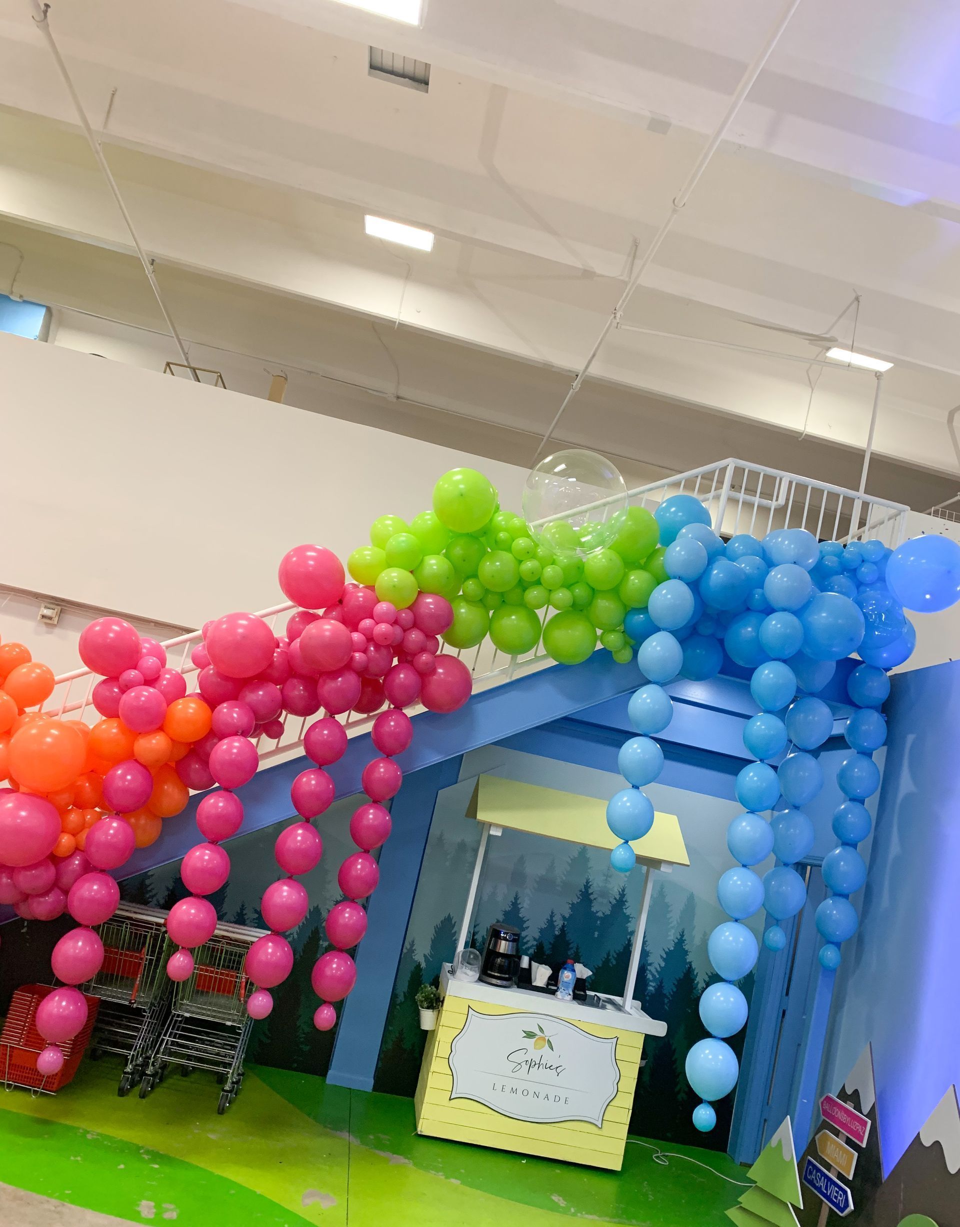 Colorful balloon arch over a play area with a food cart.