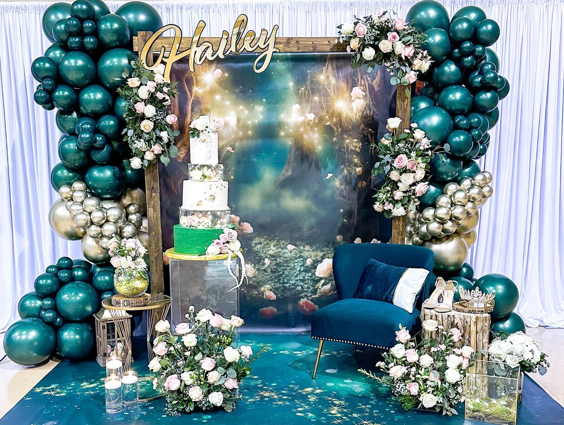 Birthday party backdrop with teal balloons, cake, and seating area.