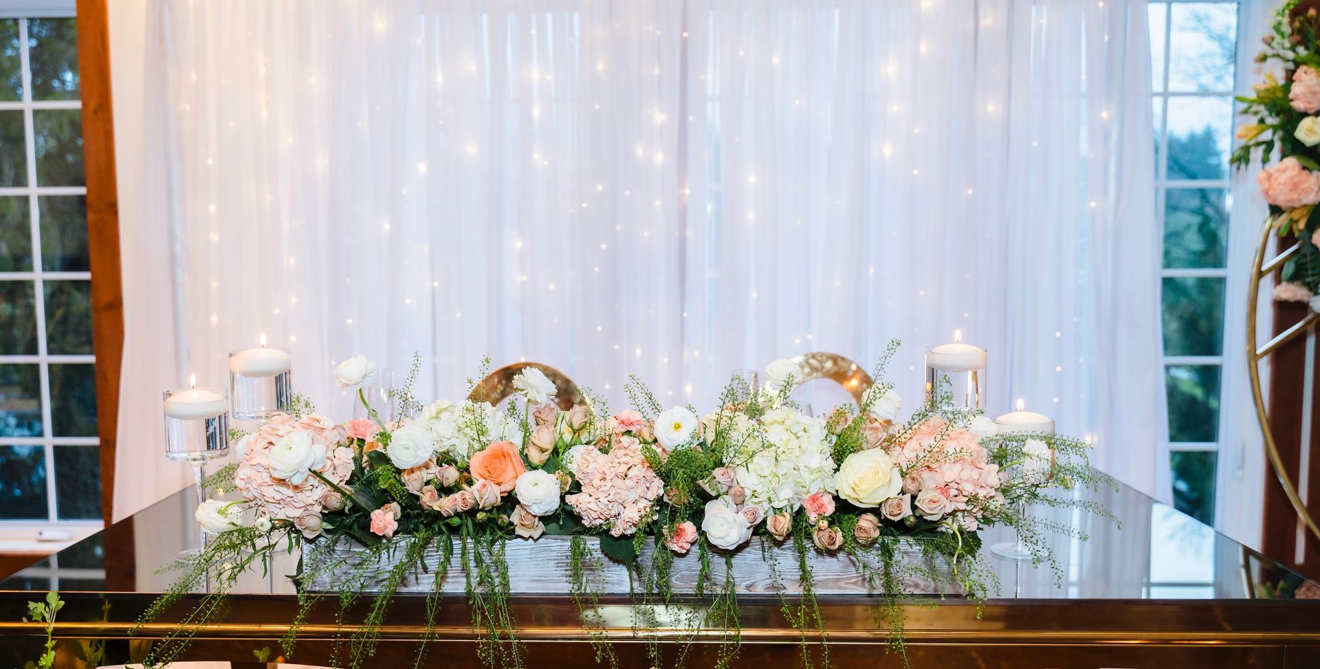 Floral centerpiece on a decorated table, with twinkling lights in the background.