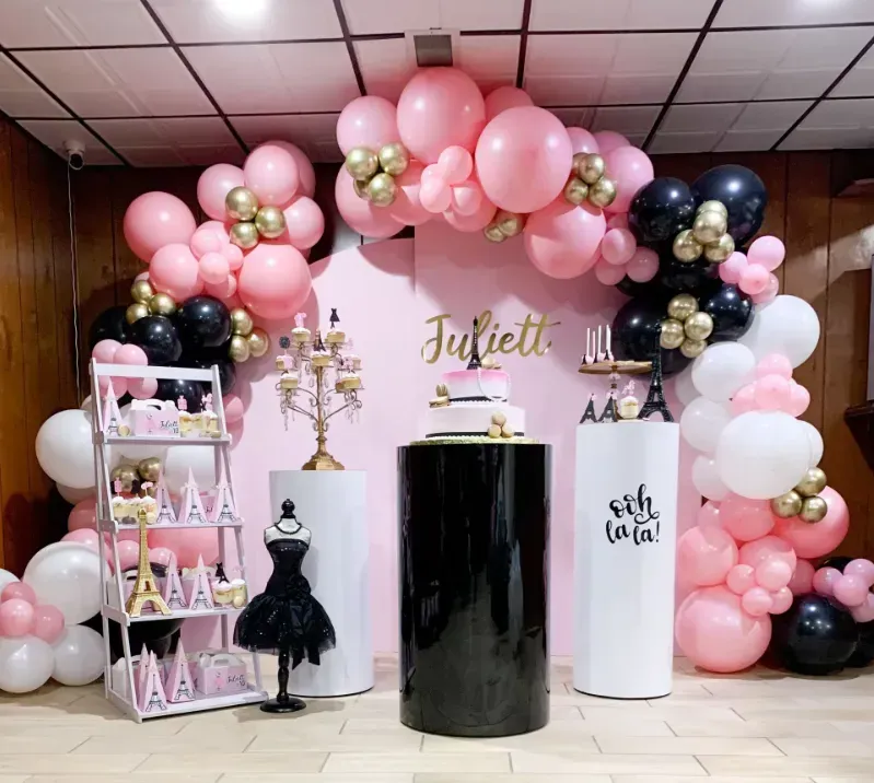 Pink, black, and gold party decorations with cake and desserts,