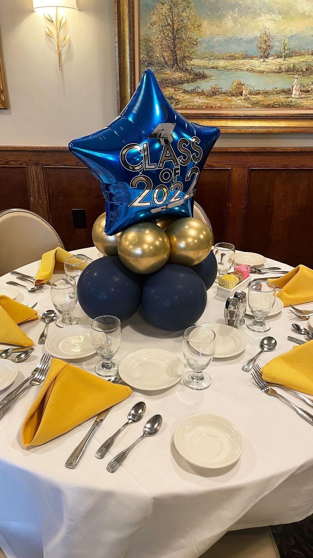 Blue star balloon centerpiece on a round banquet table set with yellow napkins and silverware