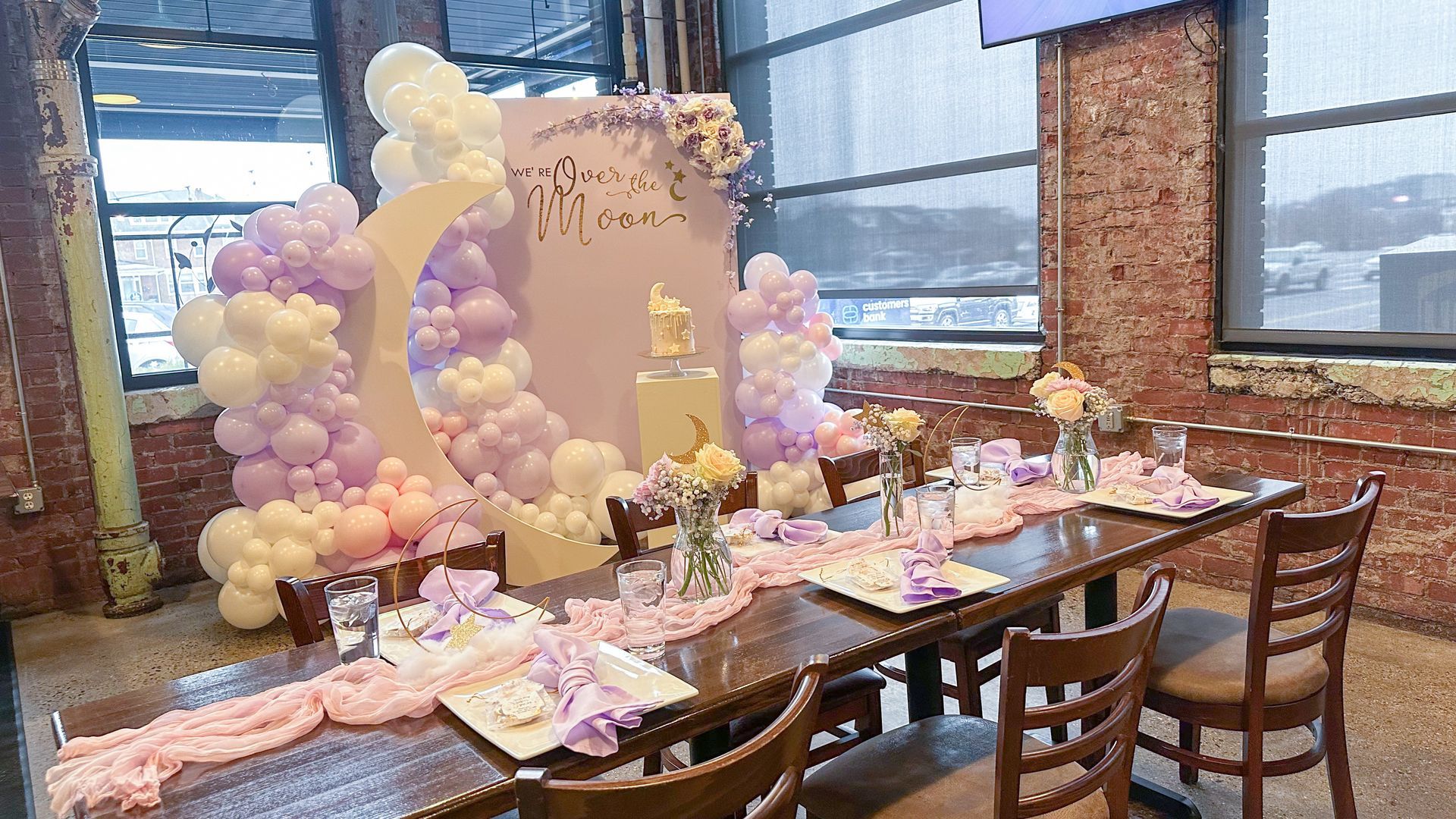 Baby Shower party backdrop: balloon arch in purple and colors with a cake on a pedestal.