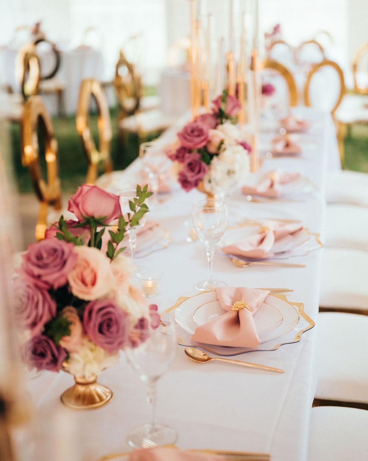 Elegant banquet table with pink rose centerpieces, white linens, and gold accents