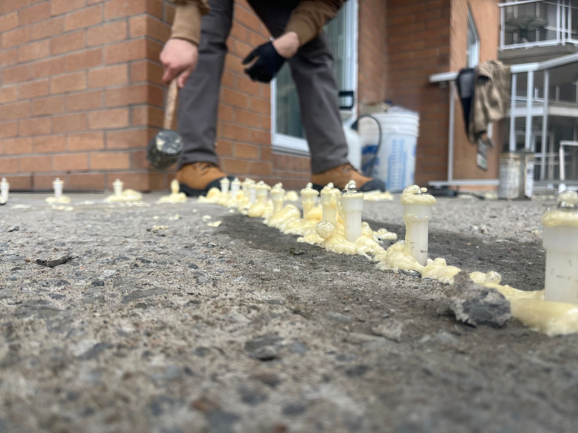 Une personne sculpte des objets en glace sur un trottoir, à côté d'un bâtiment en briques.