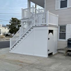 A white staircase leading up to a balcony on the side of a house.
