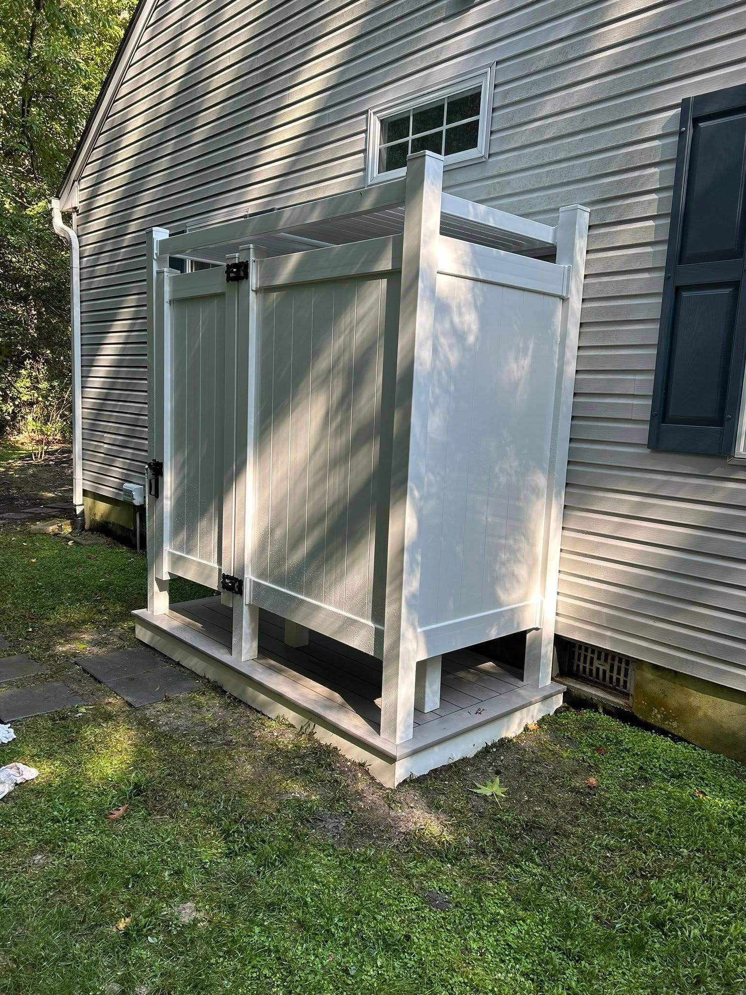 White outdoor enclosure beside a house, with screened sides and a small door on a raised platform.