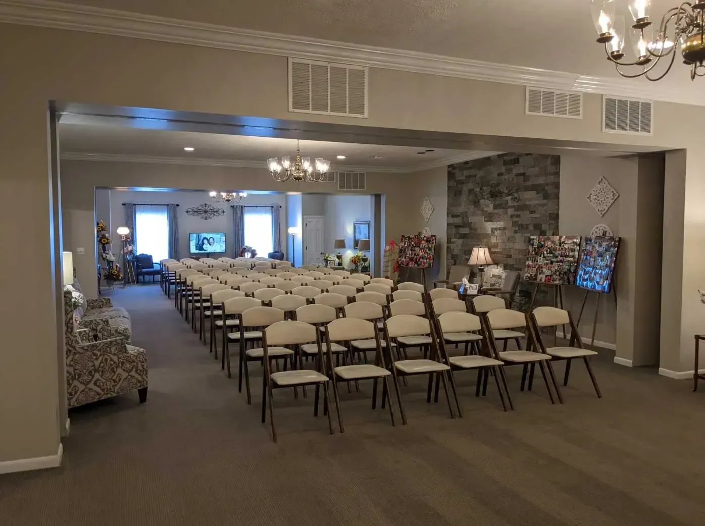 Empty banquet hall with rows of chairs facing a front wall and chandelier lighting