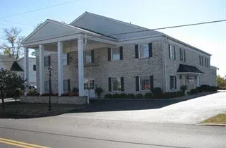 Large white-columned stone building on a street corner under a clear sky
