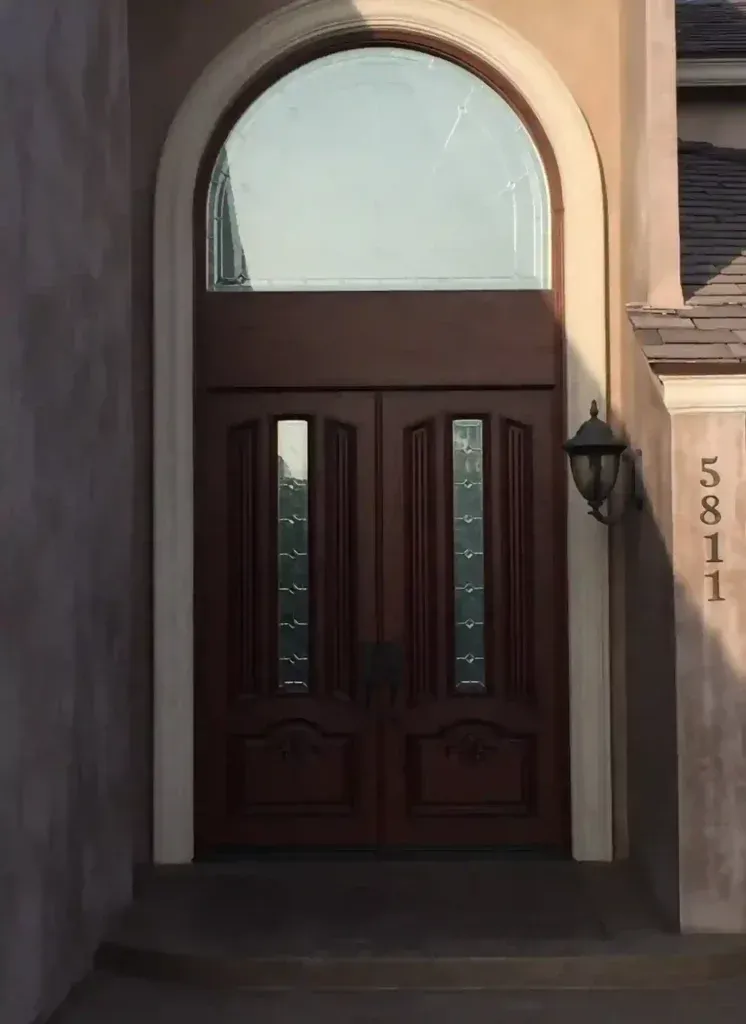 Front entrance with dark wooden double doors beneath an arched entryway and house number 5811