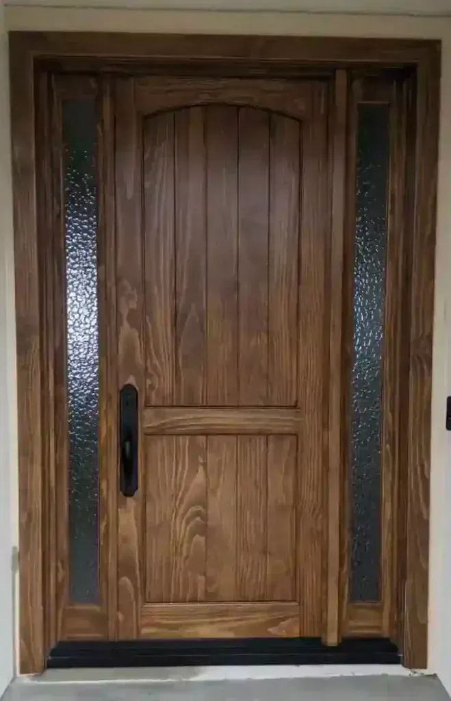 Wooden front door with frosted glass sidelights and black handle in a light-colored entryway