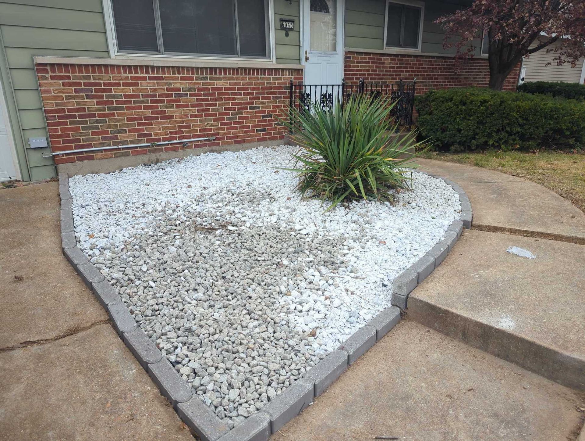 A brick house with white gravel in garden bed.