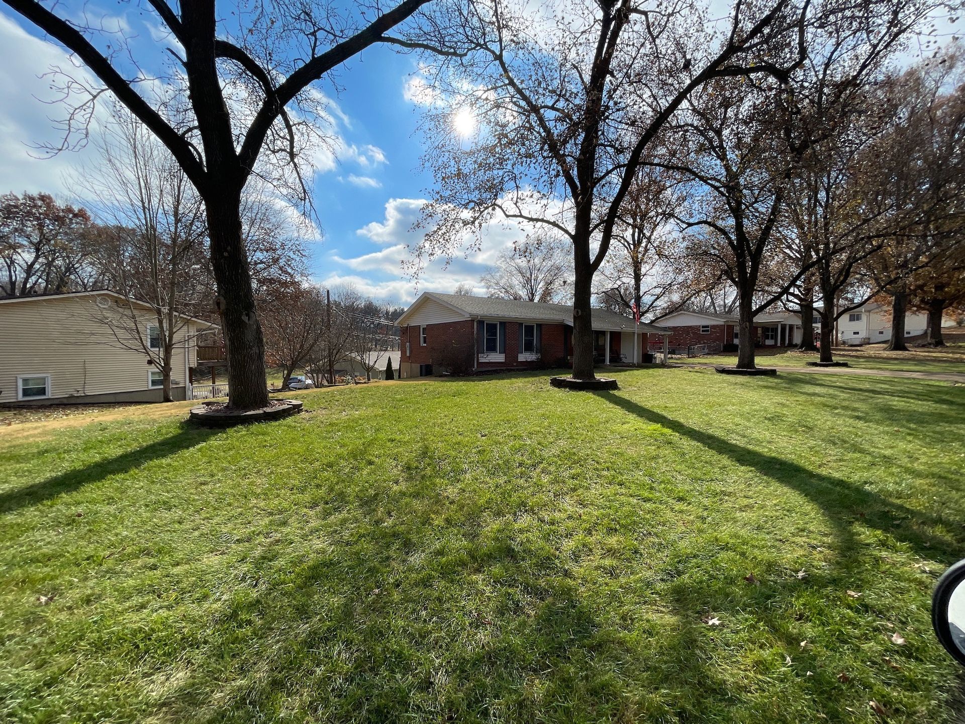 Clean and green lawn in front of a brick house.