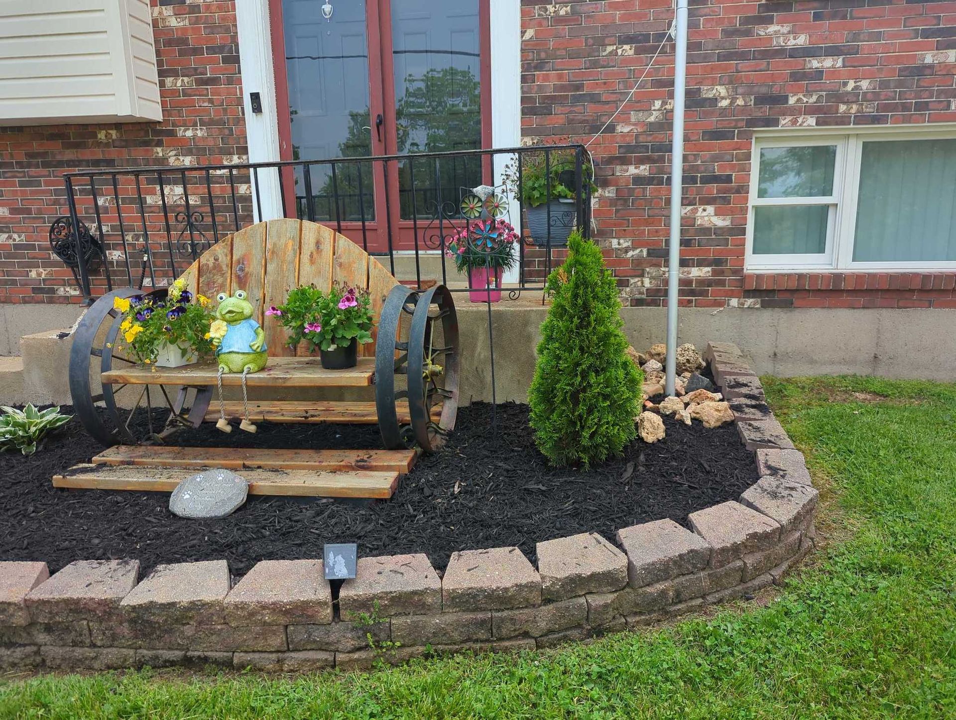 A brick house with fresh mulch inside garden bed.