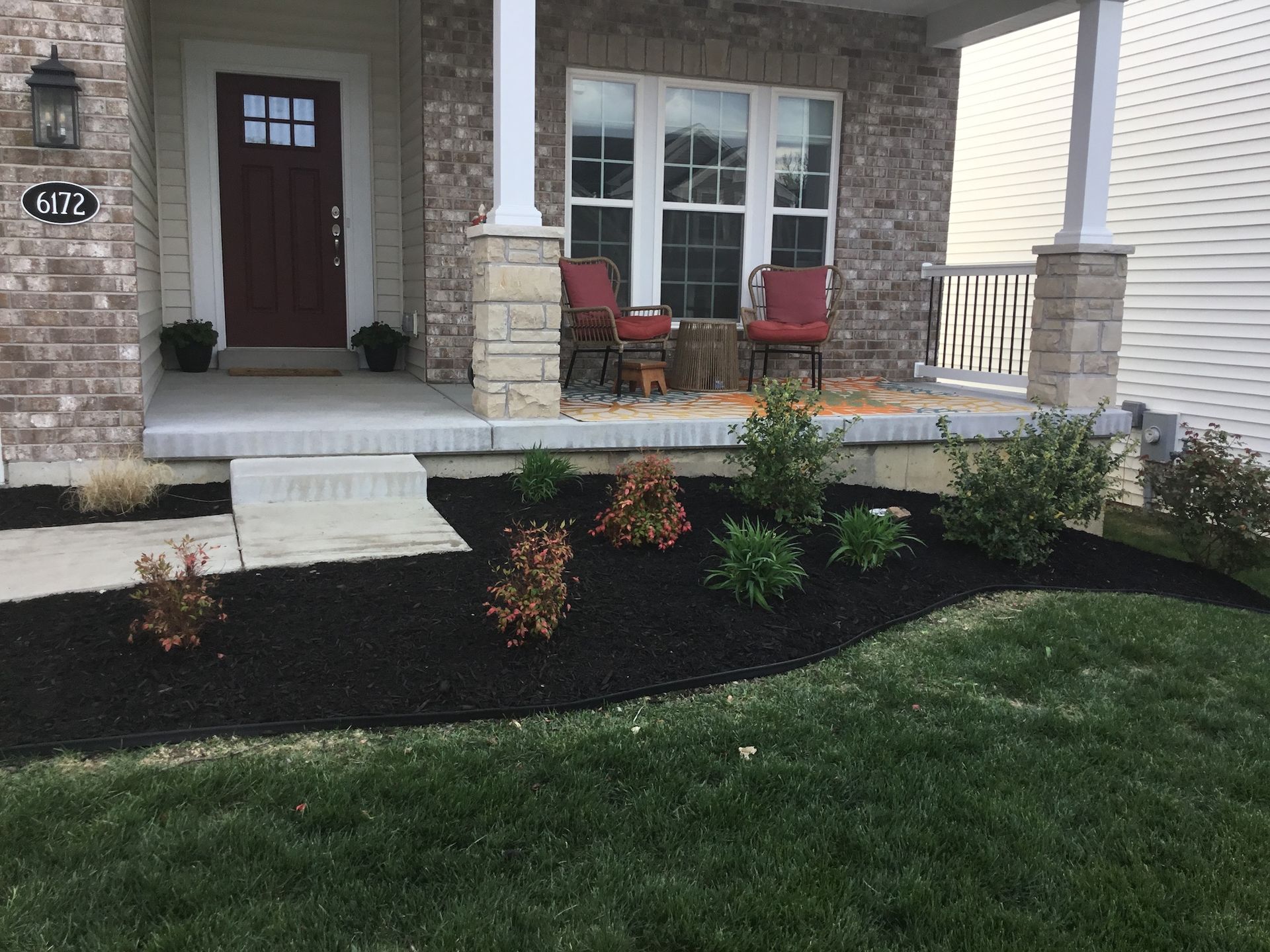Garden bed with mulch in front of porch.