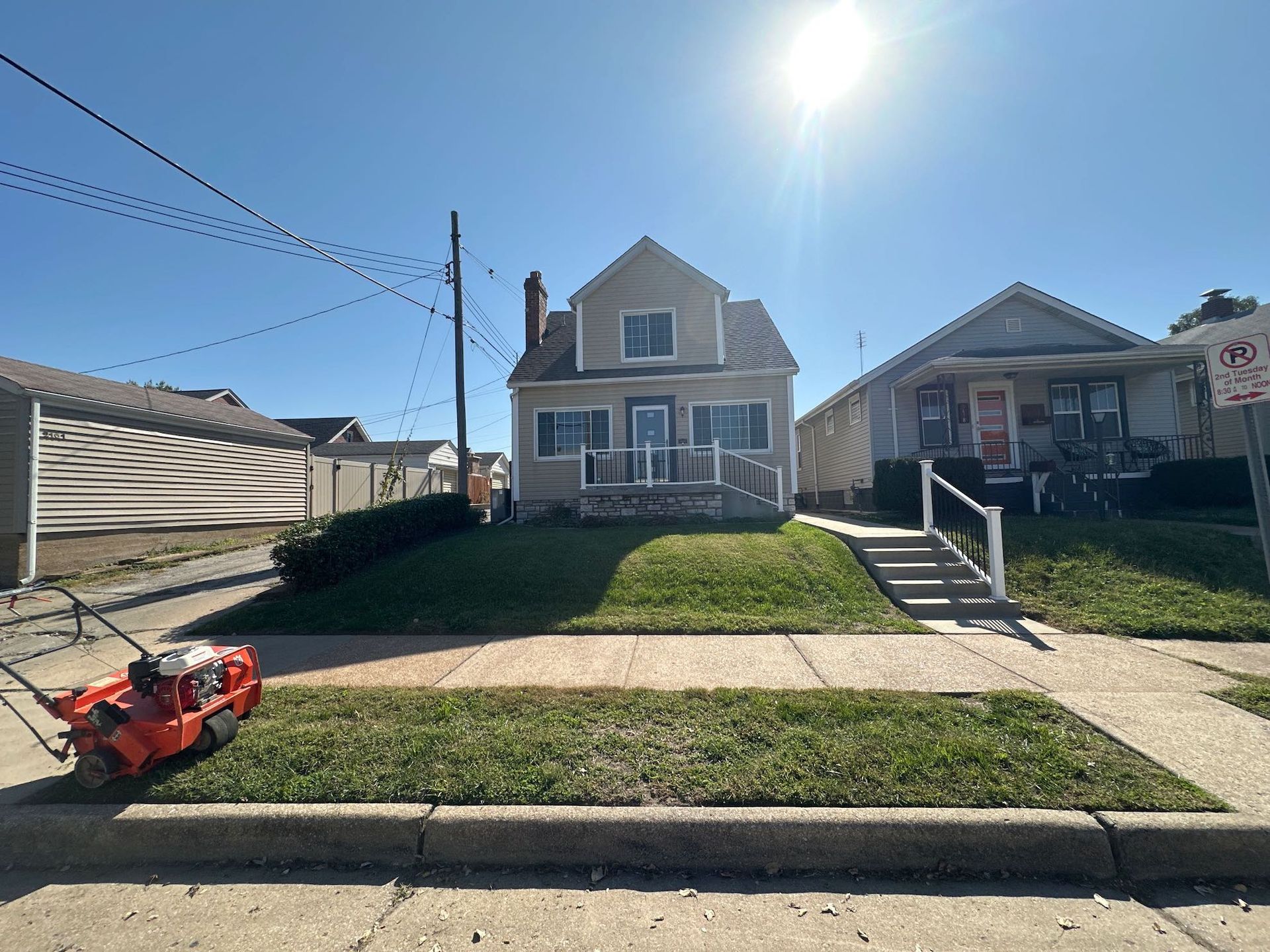 A lawn mower is parked in front of a house.