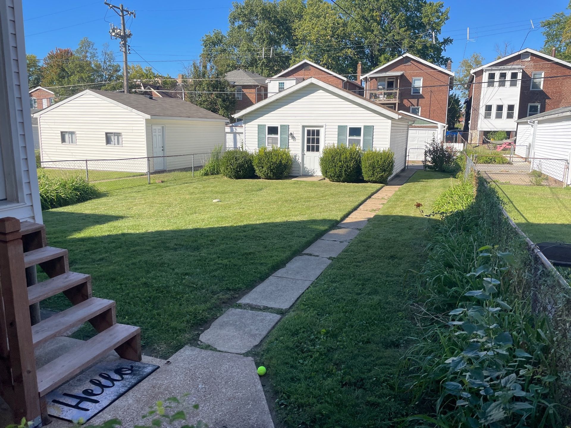 A house with a large lawn and stairs in front of it.