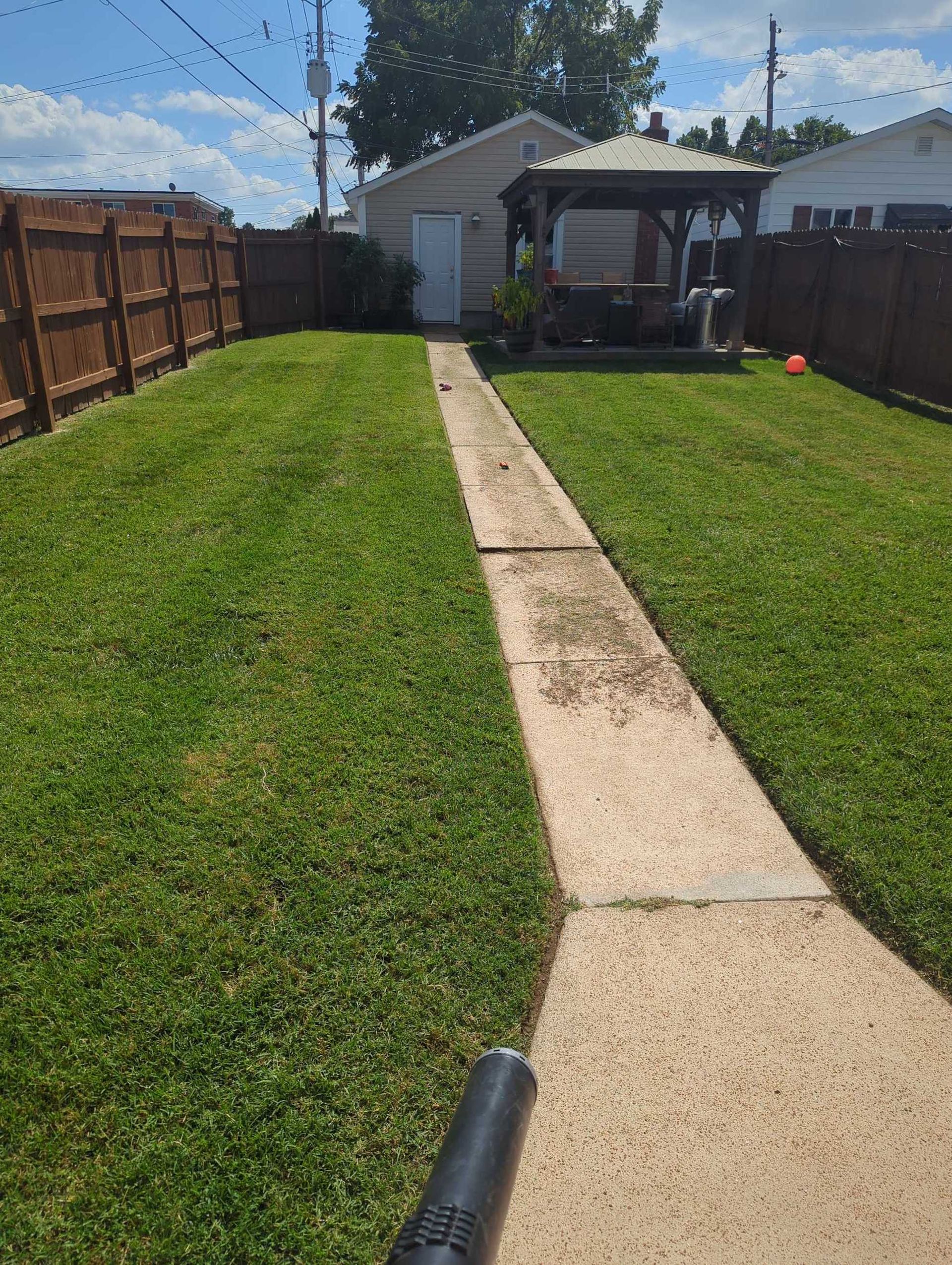 A concrete walkway leading to a house with a gazebo in the backyard. A concrete walkway leading to a house with a gazebo in the backyard.