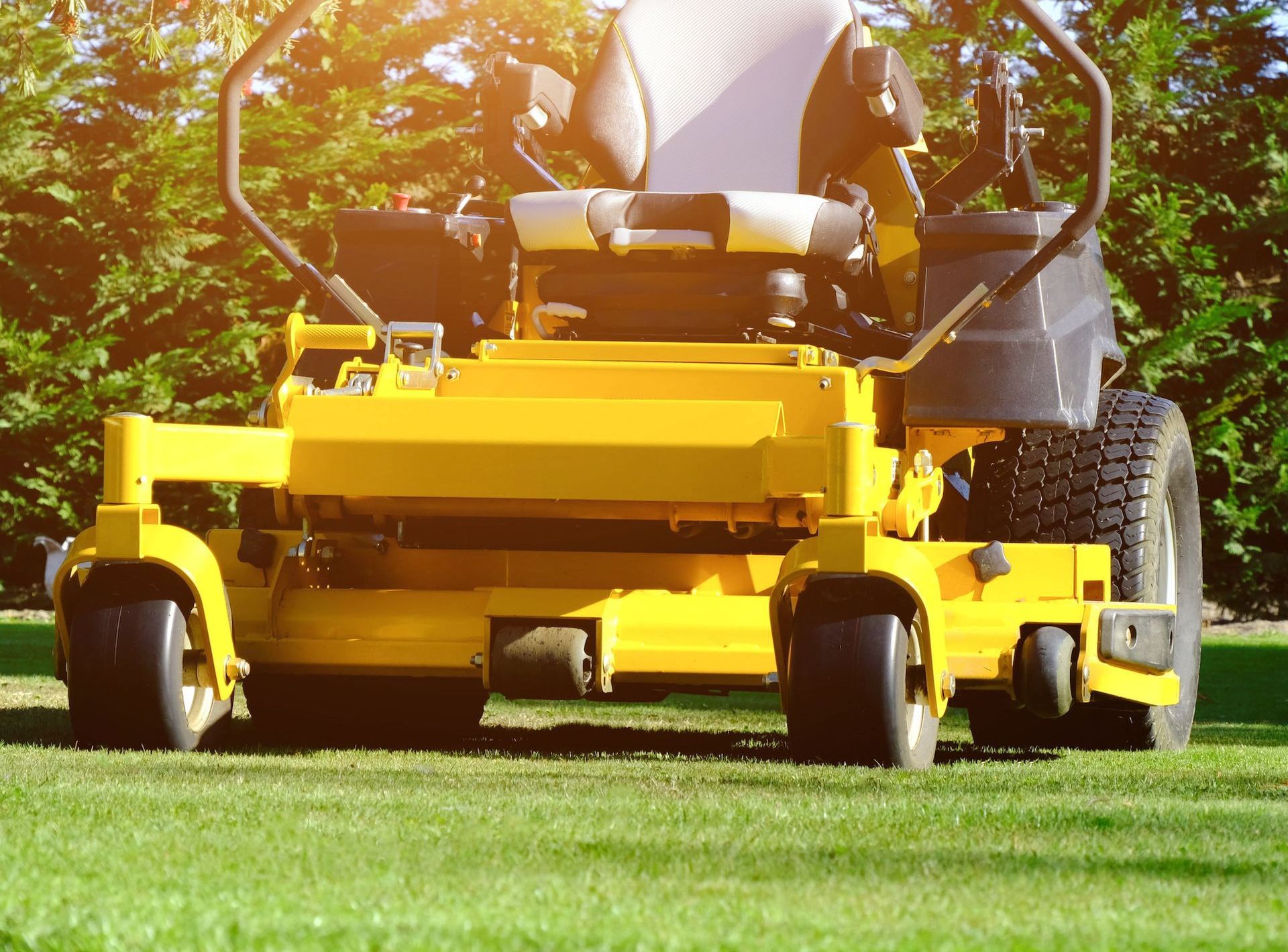 A yellow lawn mower is sitting on top of a lush green lawn.