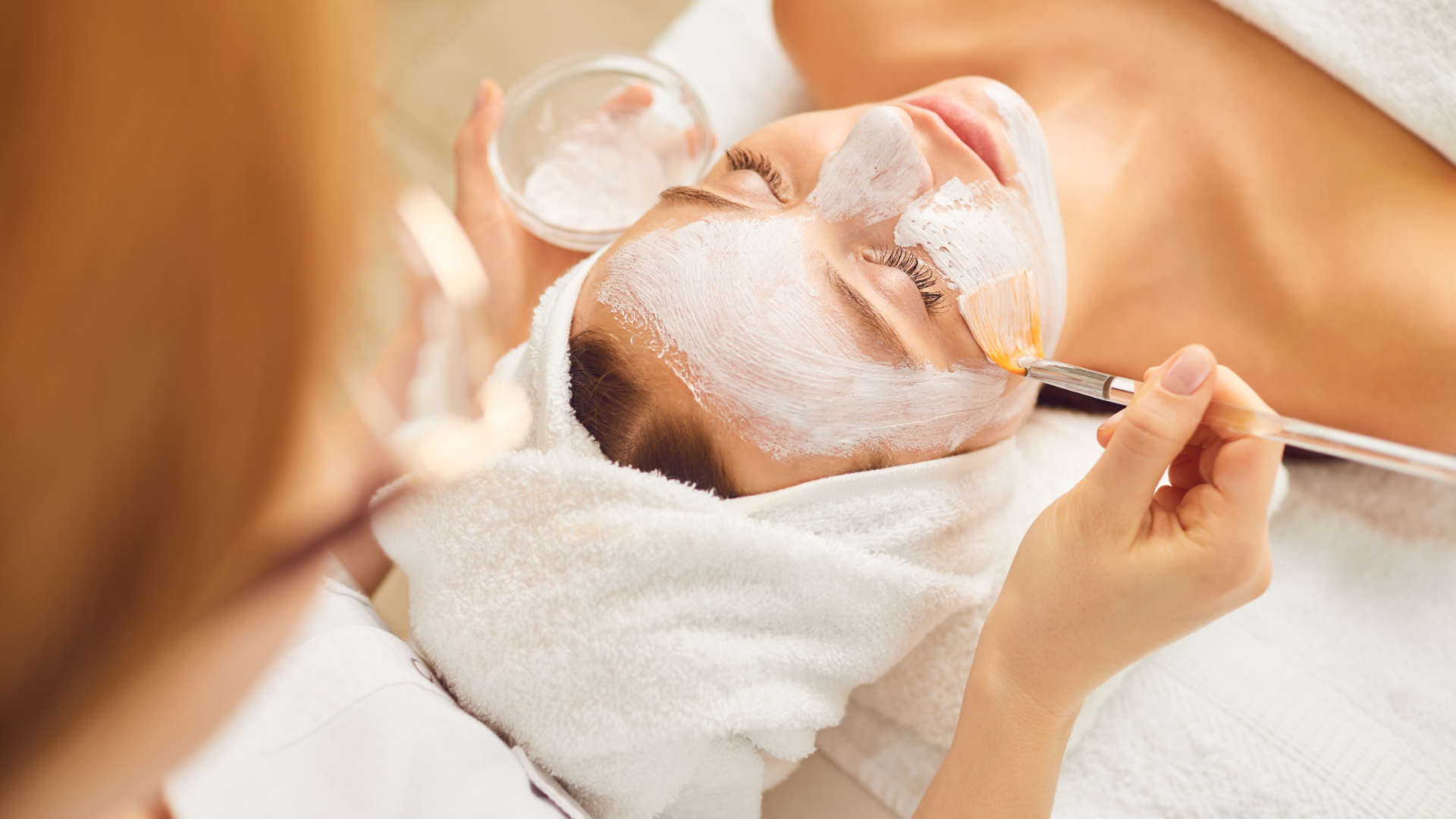 Spa facial treatment with cream and eye pads applied to a client lying on a bed