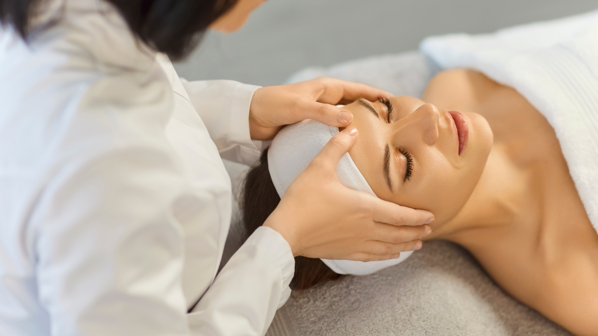 Facial treatment in a spa, with a practitioner gently massaging a client's face.