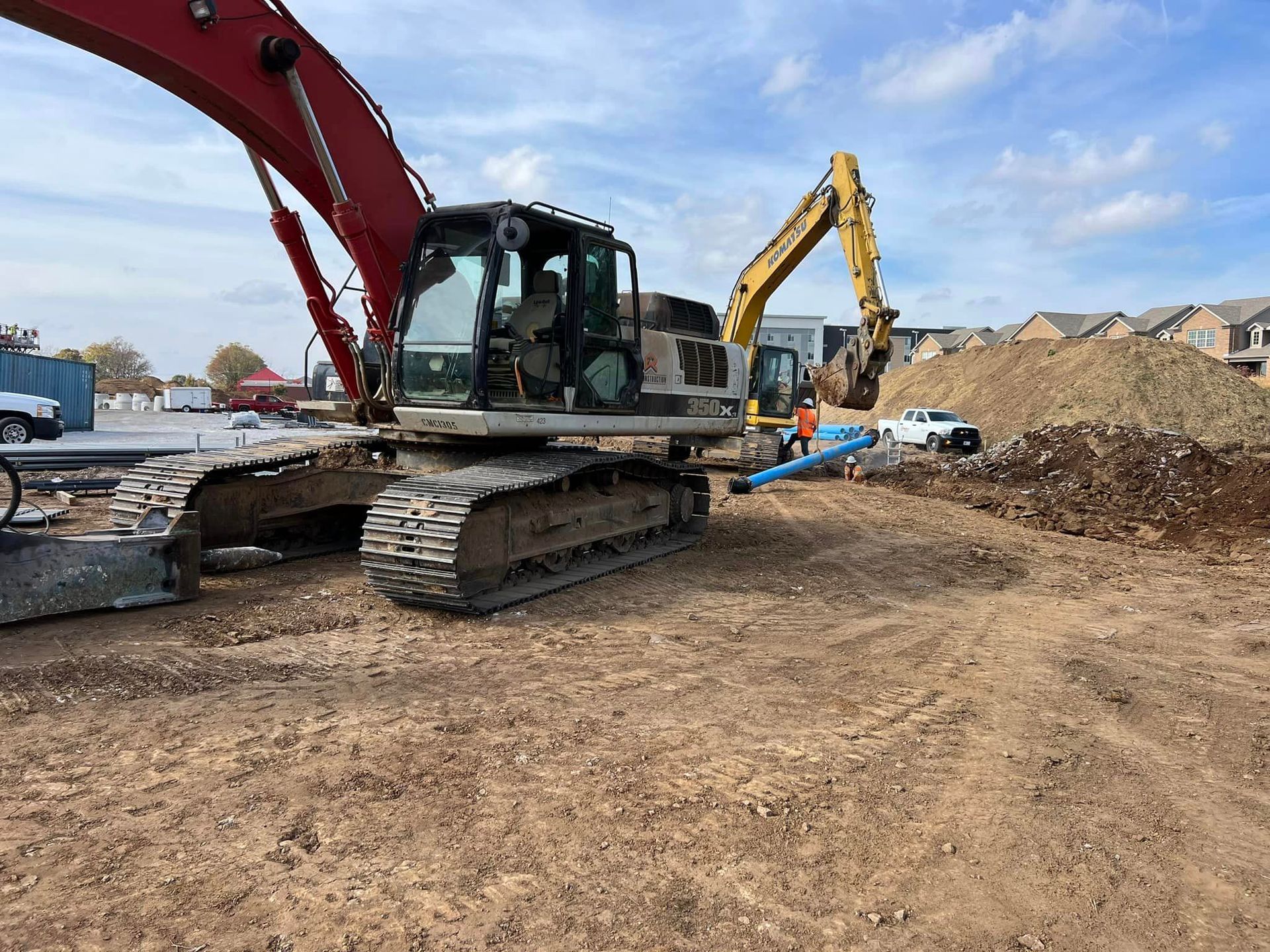 A red and yellow excavator is sitting in a dirt field.