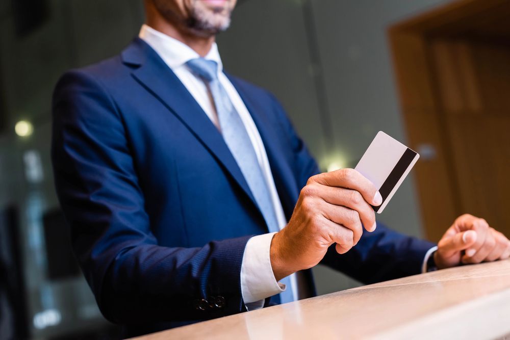 Man in blue suit handing a payment card across a counter