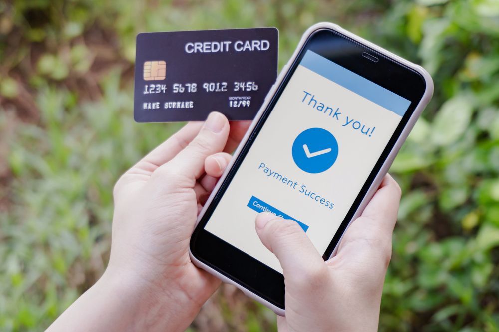 Hands holding a credit card and smartphone showing a payment confirmation screen