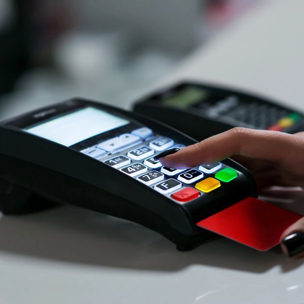 Hand using a credit card terminal with a card inserted and keypad lit up